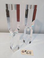 Pair of tall clear crystal candleholders standing side by side, showcasing their geometric design and height.