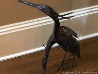 Front and side views of two metal bird sculpture exhibiting handcrafted details on birds' heads and bodies.