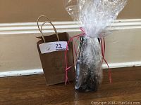 Photo of the pack of two 200 mL bottles wrapped in clear cellophane and placed next to a brown paper bag labeled Kingston Olive Oil Co.