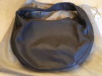 Full view of the grey pebbled leather handbag lying flat on the dust bag.