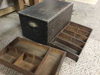 Closed antique wooden tool box shown next to removed wooden shelves with divided compartments.
