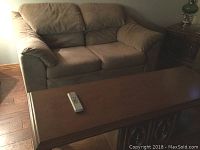 Brown fabric love seat and wooden coffee table side by side on wooden floor