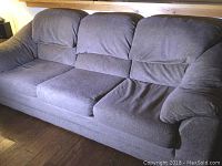 Gray fabric three-seat couch with padded armrests and three seat cushions