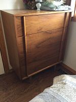 Wooden dresser with four drawers, seen from front and side angles, showing wood grain and integrated vertical handles.
