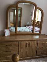 Photo of Palliser wooden dresser with attached tri-panel mirror reflecting the room.