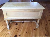 Front view of the antique chest showing carved initials and leg detailing.