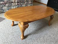 Photo of a wooden oval coffee table with carved legs in excellent condition, measuring approximately 24x46 inches.