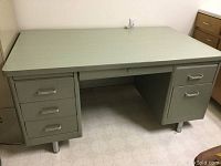 Front view of a large metal desk with six drawers, placed on a vinyl floor.