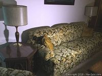 Couch with floral upholstery and cushions alongside end table and lamp