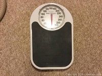 Photo of an analog Pro-Style bathroom scale with a large dial and black textured platform on a carpeted floor.