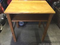 Maple wood school desk with open storage shelf, viewed from the front showing full desk with legs and surface.