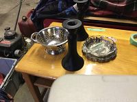 Overview showing two black metal candle holders, a small perforated metal colander, and two decorative bowls on a wooden surface.