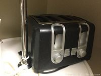 Black 4-slice electric toaster on countertop, close-up of controls and slots