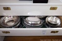 Drawer open showing sterling and silverplated bowls and platters with reflective surfaces