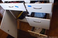 Photo showing open kitchen island drawers with various kitchen items including pots and kitchen linens piled inside.
