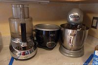 Lot includes three kitchen appliances: a Cuisinart food processor, Oster slow cooker, and Viking professional stand mixer placed on a kitchen counter.