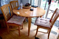 View showing round wooden dining table with four chairs having striped cushions, located near sliding glass door.