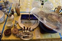 View of table with crystal Passover cups, metal trivets, lidded bowls, salt and pepper shakers, cuff links, and other small kitchen and decorative items.