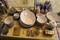 Overview of assorted bowls in white ceramic alongside decorative blue and white transferware items and small miscellaneous trinkets.