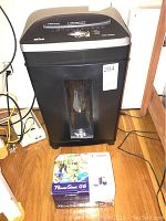 Ativa DS130C paper shredder in black and silver with a translucent bin window and Canon PowerShot G6 box in front on wooden floor.