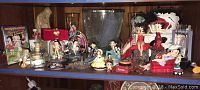 Wide shot showing collection of Betty Boop figurines, glassware, plush toy, DVD, and other collectibles arranged on a shelf.