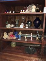 Full view of wooden cabinet shelves displaying assorted decor items including figurines and vases.