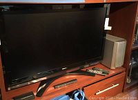 Toshiba 47 inch flat screen TV on a wooden media console with soundbar and remotes.