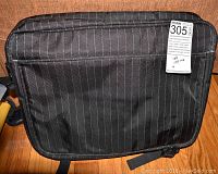 Front view of black pinstriped nylon carrying case with lot tag attached