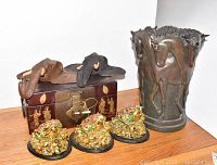 Photo showing horse-themed vase, wooden chest with abacus, elephant head mounts, and gold frog figurines.