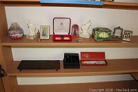 Two wood shelves with assorted decor items including elephant bookends, clocks, sand art jar, boxed chopsticks, letter openers, and decorative boxes