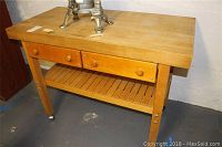 Front view of wooden butcher block table showing two drawers and lower slatted shelf