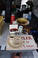 Photo showing Sizzler dishes, mugs, ashtray, and various home decor items including soldier figurines and music boxes.
