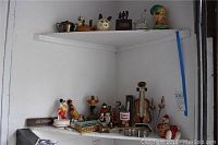 Wide shot of shelf with various home decor figurines, decorative boxes, and memorabilia items including a violin music box.