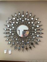 Front view of the round sunburst mirror with multiple small mirror elements arranged in a radial pattern around a central mirror, mounted on a wall.
