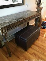 Full side view of rectangular table with dark brown marble top and inset carved wooden legs and apron, showing detailed wood carvings and general condition