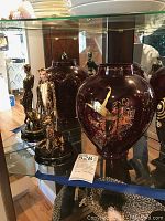 Upper cabinet shelf with two burgundy Erte vases and two Erte porcelain figurines