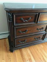 Front angle view showing nine drawers with decorative metal handles and carved corner details on the dresser side
