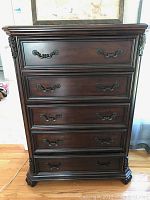 Front view of Liberty Furniture tall dresser showing the five drawers with metal handles and carved corner details.