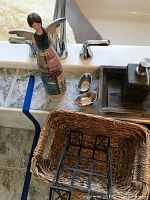 View of woven basket, angel makeup case, silver accent bowls, and slate soap dispenser by bathtub.