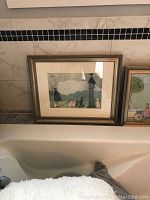 Photo showing framed print of figure and rabbits near clock tower next to bathtub