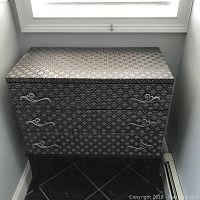 Full front view of chest showing top, three drawers with handles, and patterned exterior.