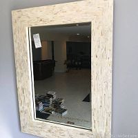 Full frontal image of the tile frame mirror showing rectangular shape, beige and cream tile frame, and reflection of room interior.
