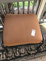 Close-up of one ottoman with rust-colored cushion on metal frame