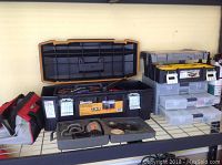 Wide shot of the lot showing the open Bostitch toolbox with tools inside, two plastic drawer organizers, and a canvas-style tool bag on a wire shelf