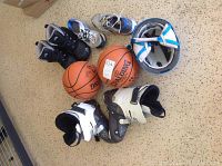 Photo displaying all items in the lot with basketballs, boots, sneakers, and helmet arranged on the floor.