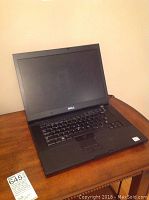 Closed laptop on wooden table with tag in front showing lot details.