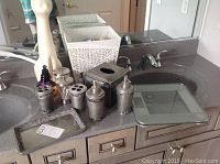 Full view of bathroom countertop with the scale, wastebasket, cat toilet brush holder, various pewter bathroom accessories with mirrored mosaic motif arranged on the counter.