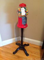 Full view of the 36-inch tall gumball machine showing red metal body, glass globe filled with gumballs, and black metal stand with four feet.