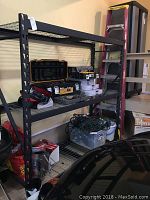 Full view of the large metal utility shelf with various stored tools and equipment.