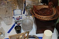 Photo of mixed kitchen items on table showing clear glassware, woven baskets, and wooden box.